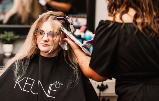 modern background stylist, focused expression, organizing a bookshelf, photorealistic, minimalist office space with sleek furniture and a large window, highly detailed, sun rays streaming in, crisp focus, monochromatic colors, bright morning lighting, shot with a 24mm wide-angle lens.