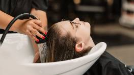 art deco stylist decor, cheerful expression, adjusting a lamp, photorealistic, retro-themed living room with geometric patterns and surrealistic paintings, highly detailed, faint sound of music implied, dynamic shadows, bold primary colors, moody evening lighting, shot with a 28mm wide-angle lens.